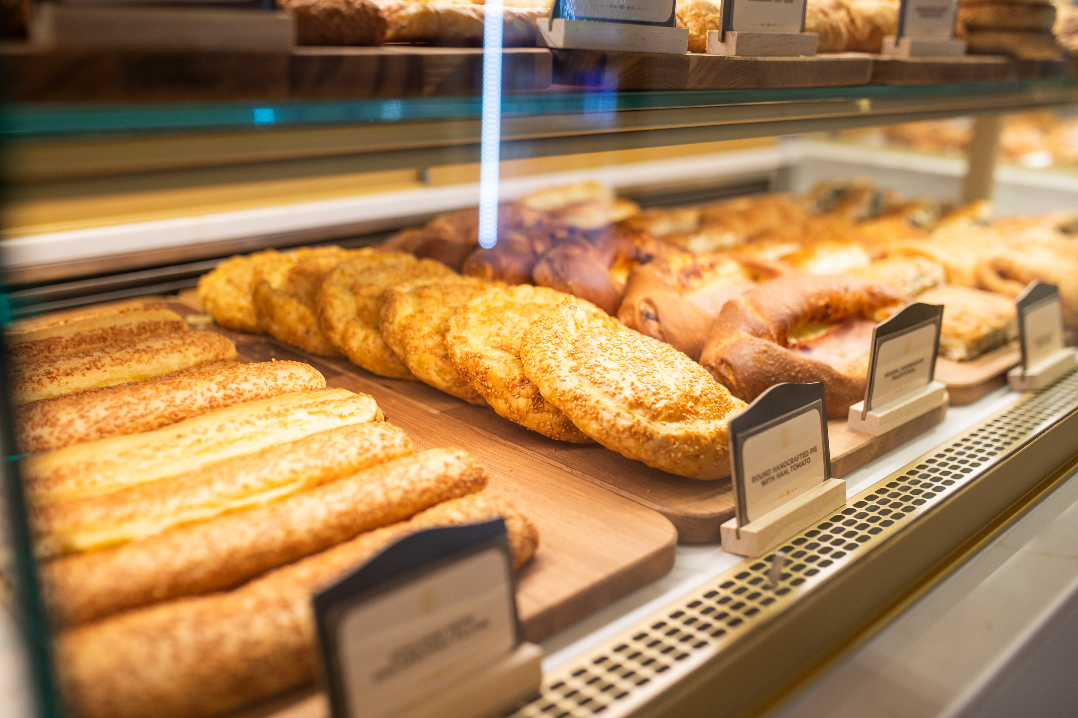 The Adore Bakery savoury counter — golden cheese rolls and freshly baked savouries on wooden boards