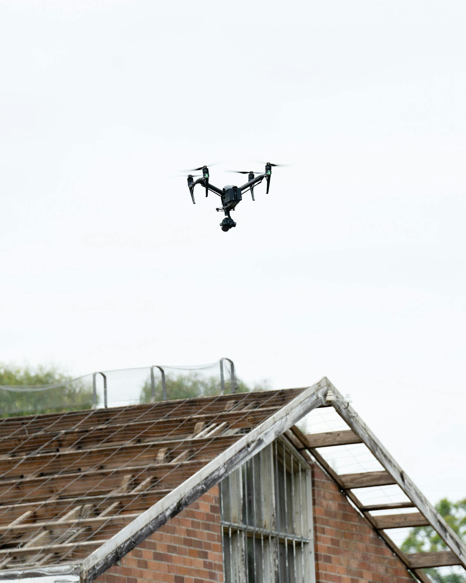 Drone hovering above a building roof during inspection.