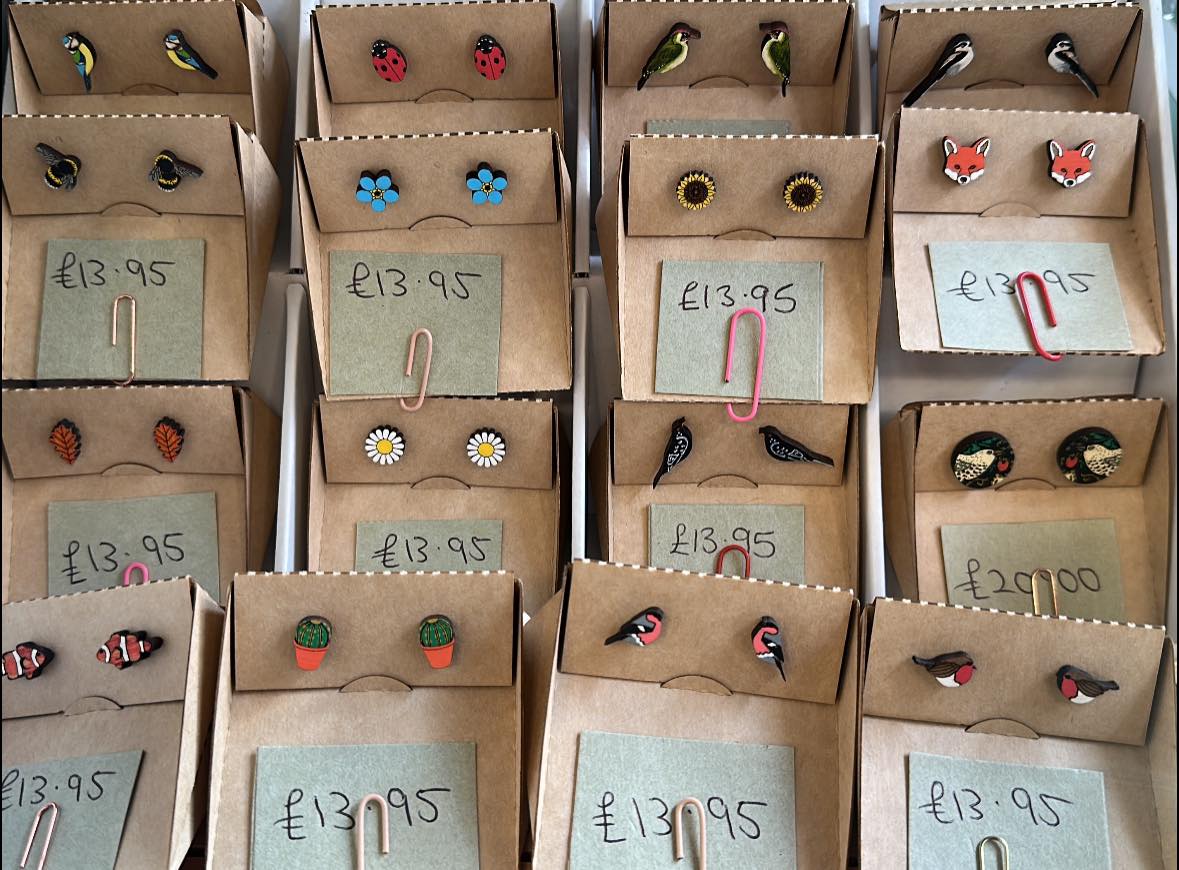 Display of hand-painted wooden stud earrings at Googie's — birds, foxes, ladybirds, sunflowers and daisies