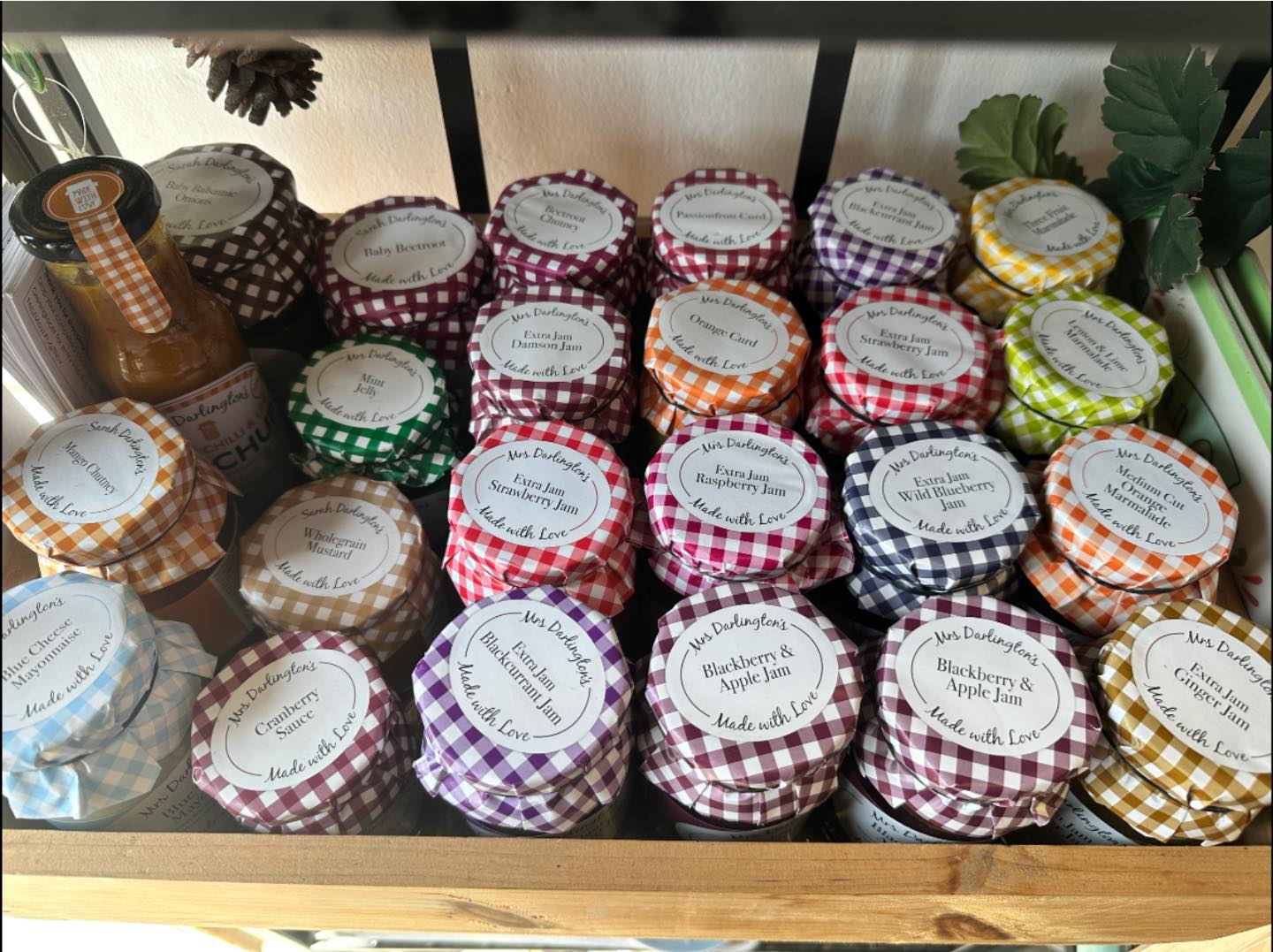 Shelf of Mrs Darlington's preserves at Googie's — jams, curds, chutneys and marmalades in gingham-topped jars