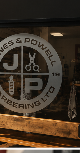 JP Barbering shop window with the Jones & Powell roundel etched on the glass, wood-panelled interior behind